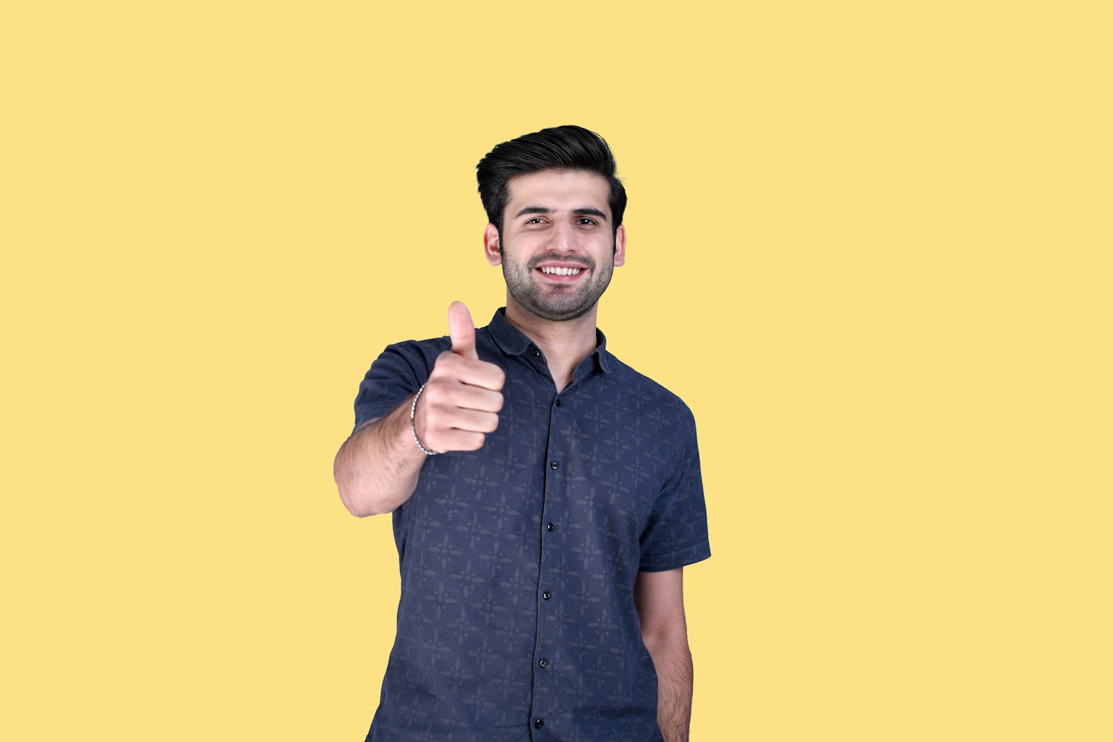 A neon-illuminated hand giving a thumbs up against a vibrant gradient background, symbolizing approval and positivity.