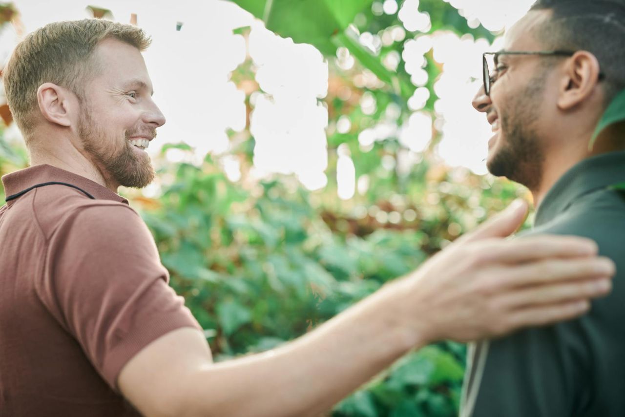 Two men enjoying a friendly and happy moment in a lush green environment.